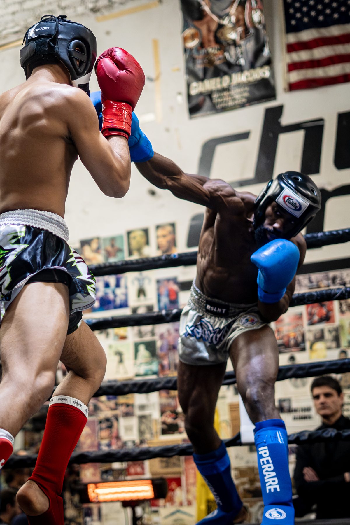 Two fighters trading in headgear, crowd tight behind the ropes