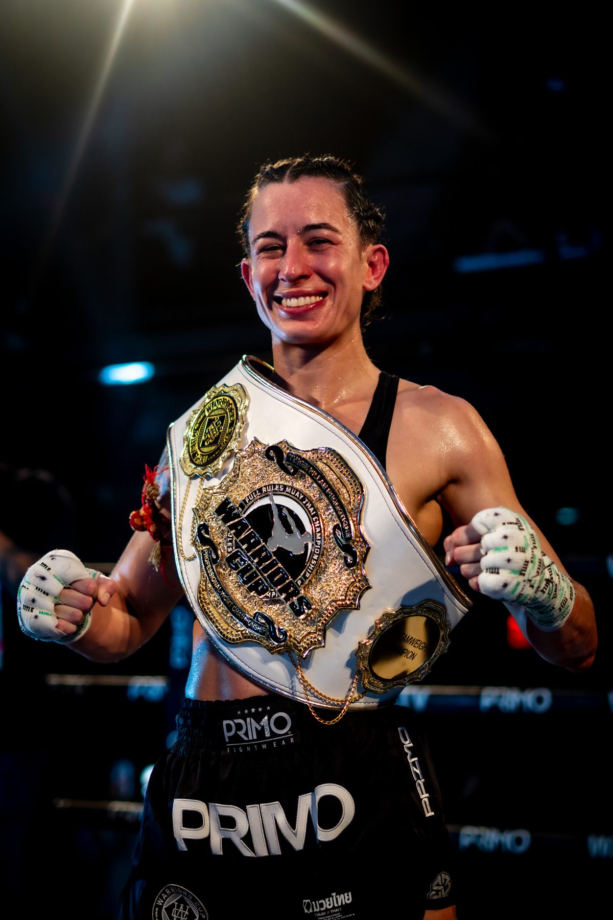 A champion in the ring with the title belt across her shoulder