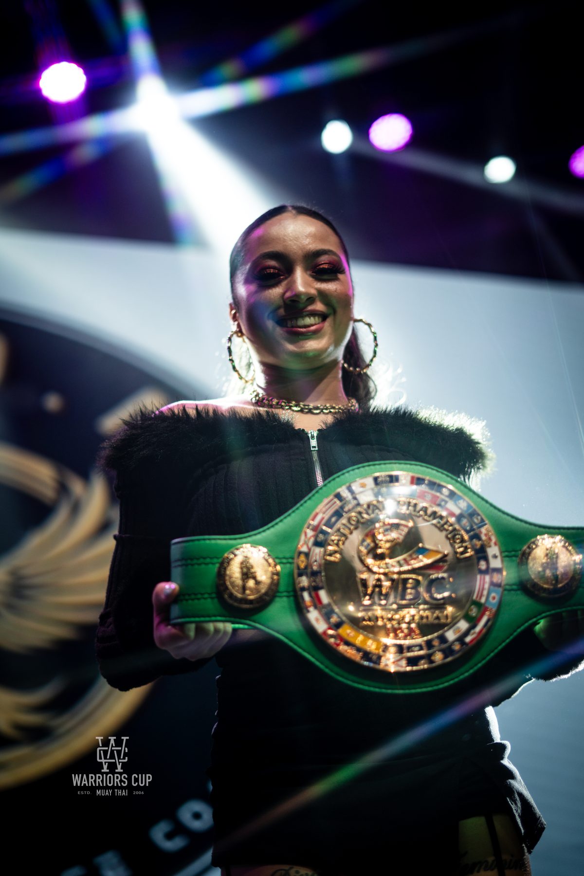 A fighter holding up her title belt after the decision