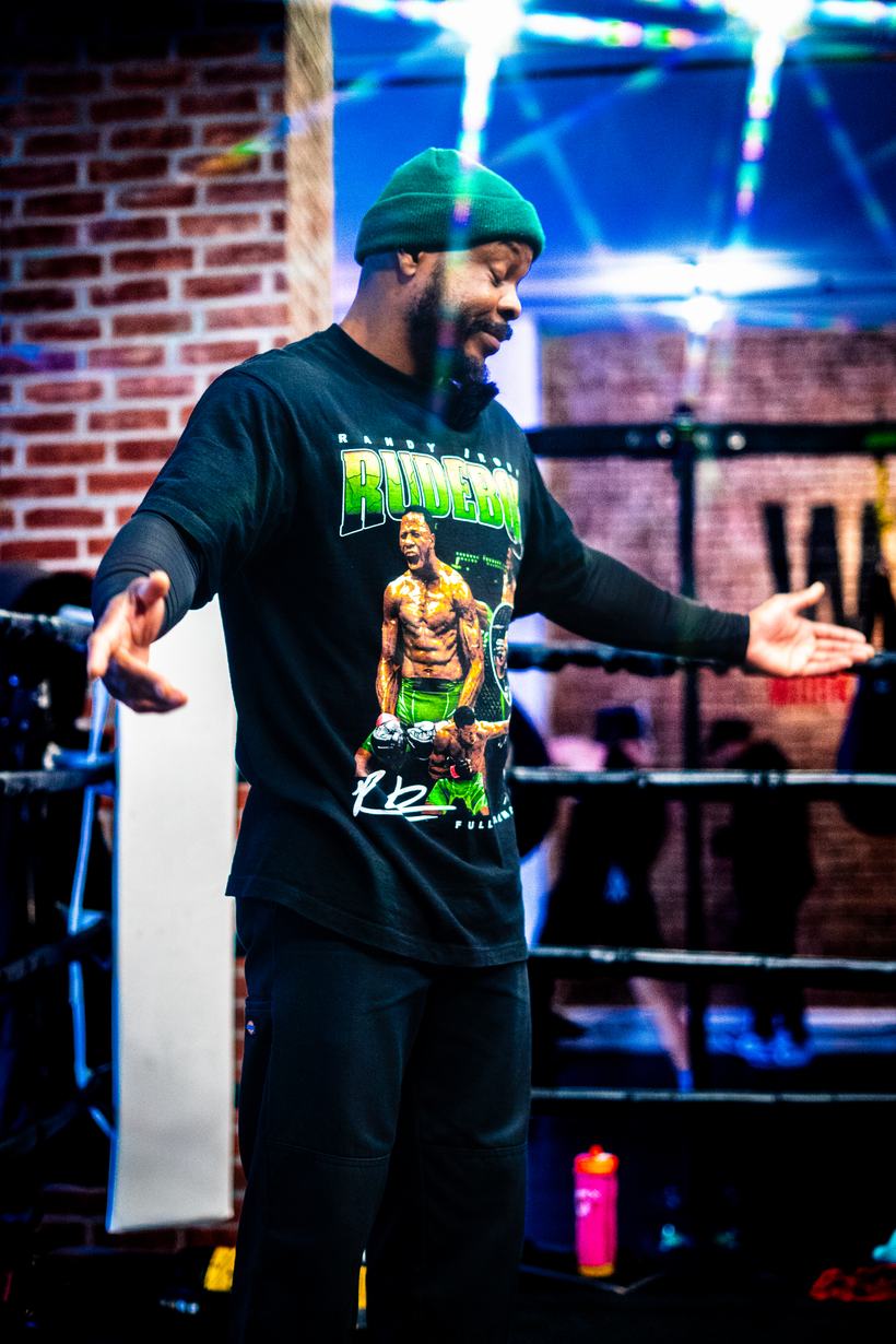 Host working a small venue crowd, arms open mid announcement