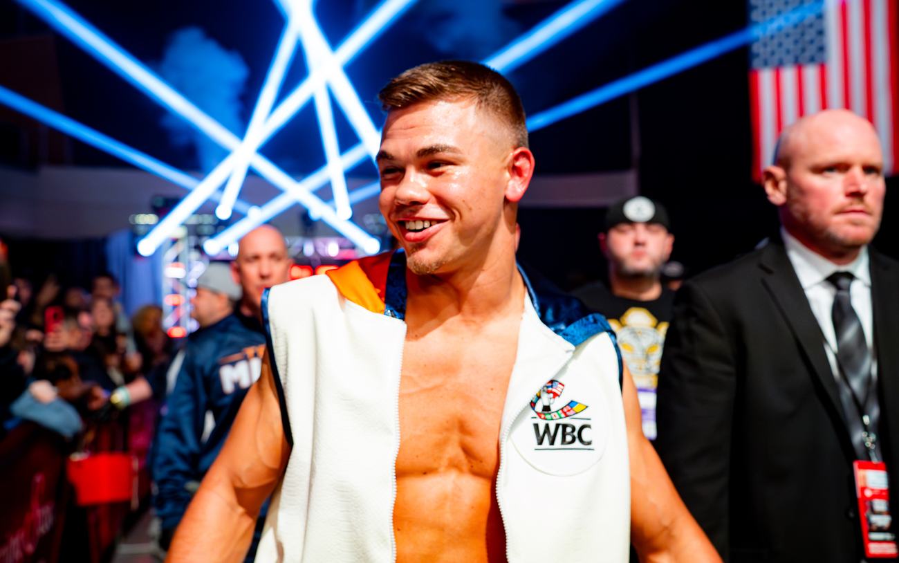 Fighter smiling in his robe with a WBC patch, towel draped on