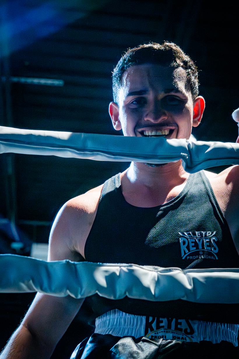 Fighter grinning through the ropes, mouth on the top strand