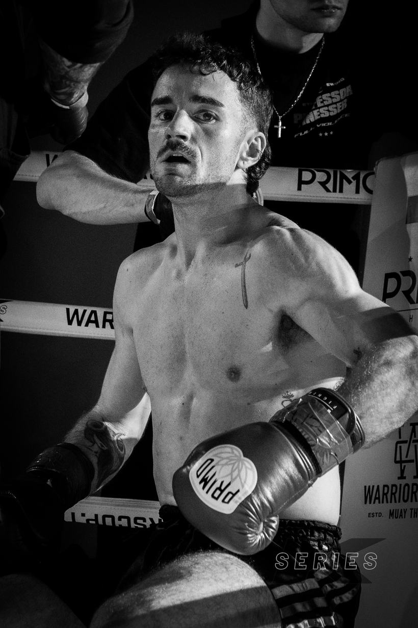 Fighter resting a glove on the ropes, still breathing hard