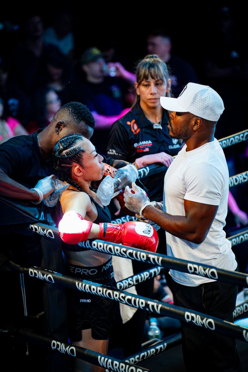 Fighter taking water between cornermen at the ropes