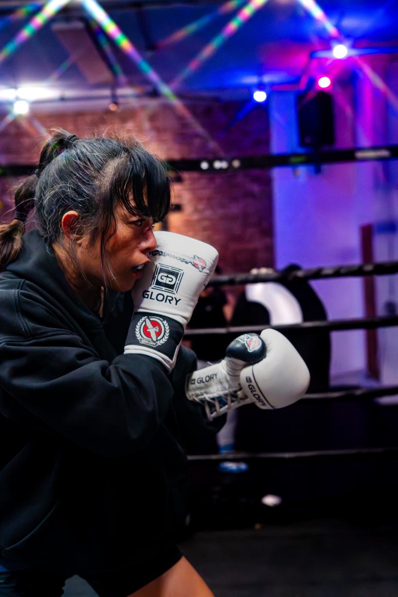 Fighter set behind her gloves in a tight guard stance