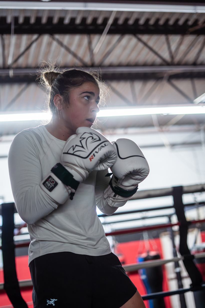 Fighter set behind her guard between rounds on the pads