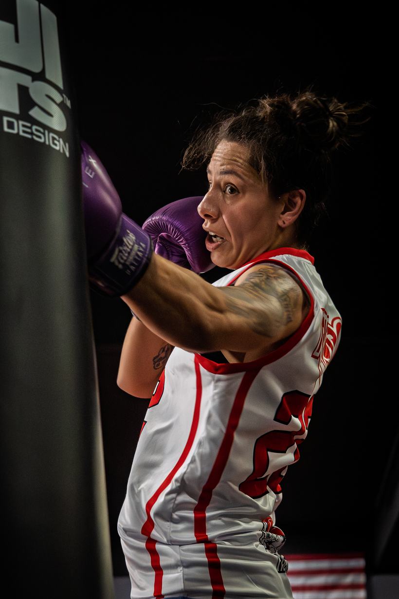Boxer working the heavy bag under gym lights