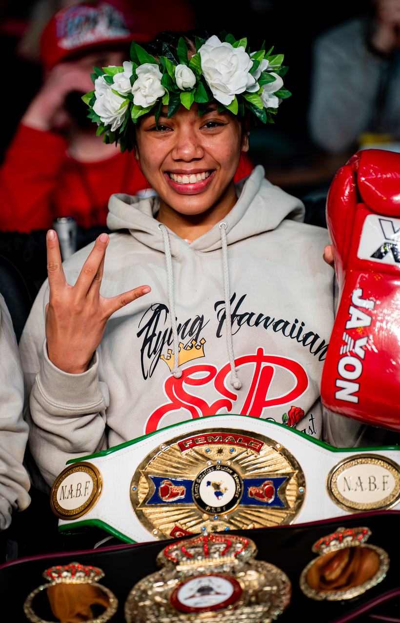 Champion with a flower crown and three title belts